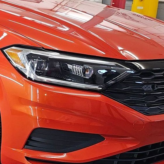 A man is cleaning a white car with a sponge.