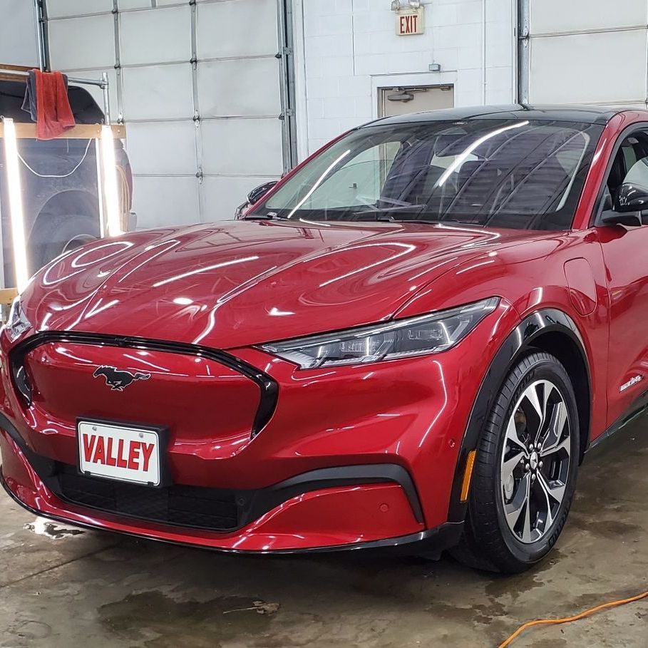 A gray car is parked in a garage with its doors open.