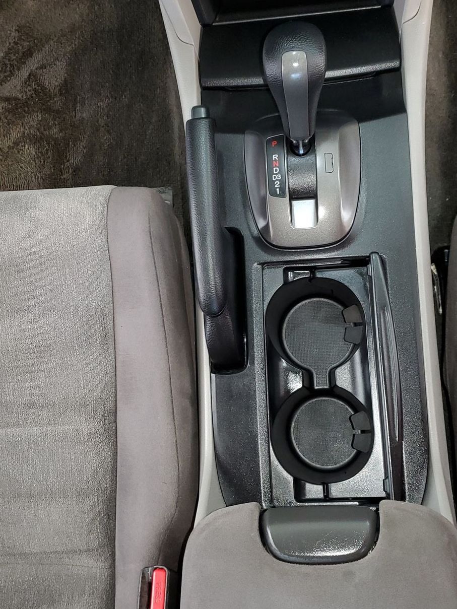 A car console with two cup holders and a shifter