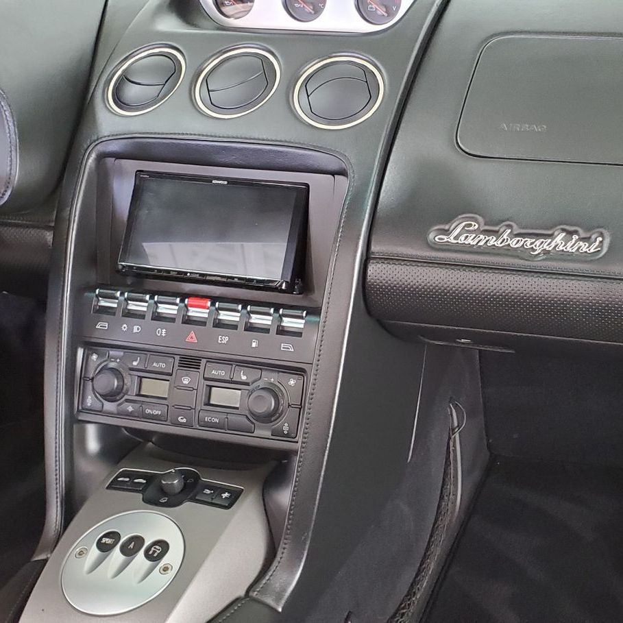 A man is cleaning the seats of a car with a vacuum cleaner.