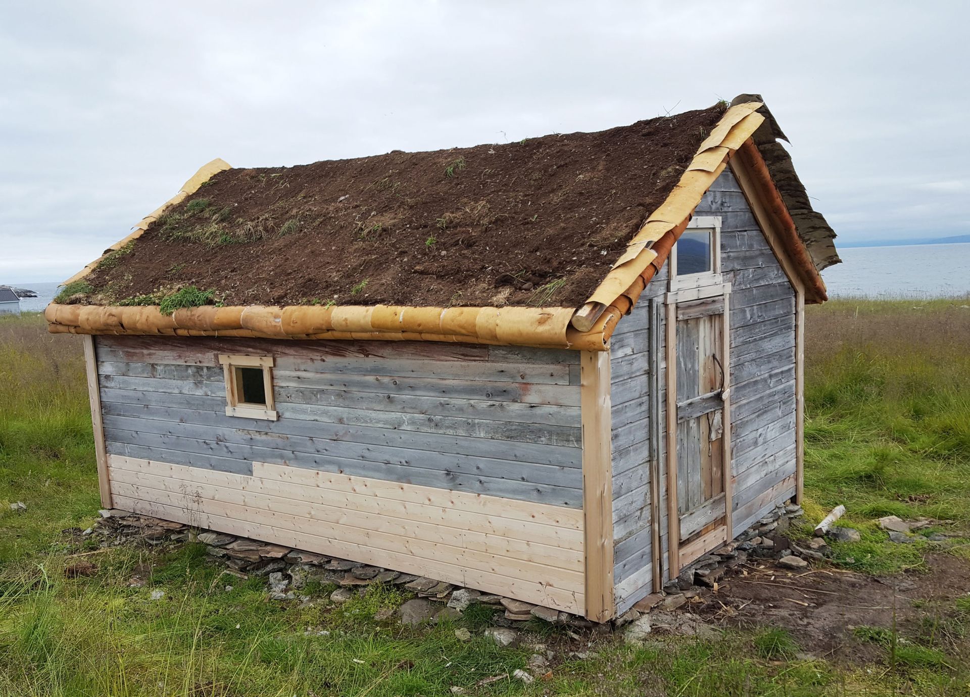 Et lite trehus med torvtak.