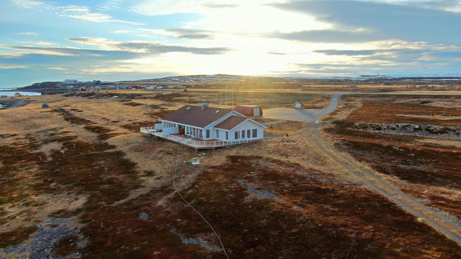 Et dronefoto av et større bygg, sola skinner.