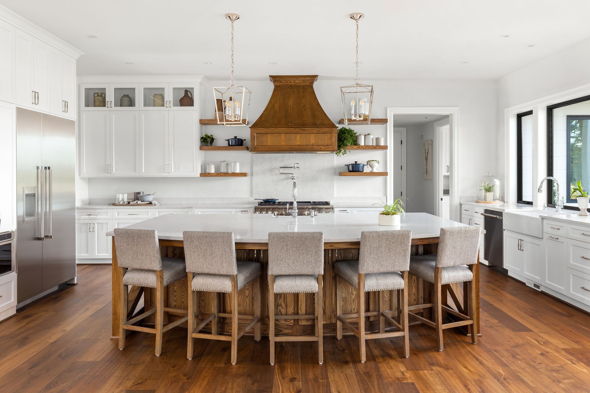 A kitchen with white cabinets , stainless steel appliances , hardwood floors and a large island.