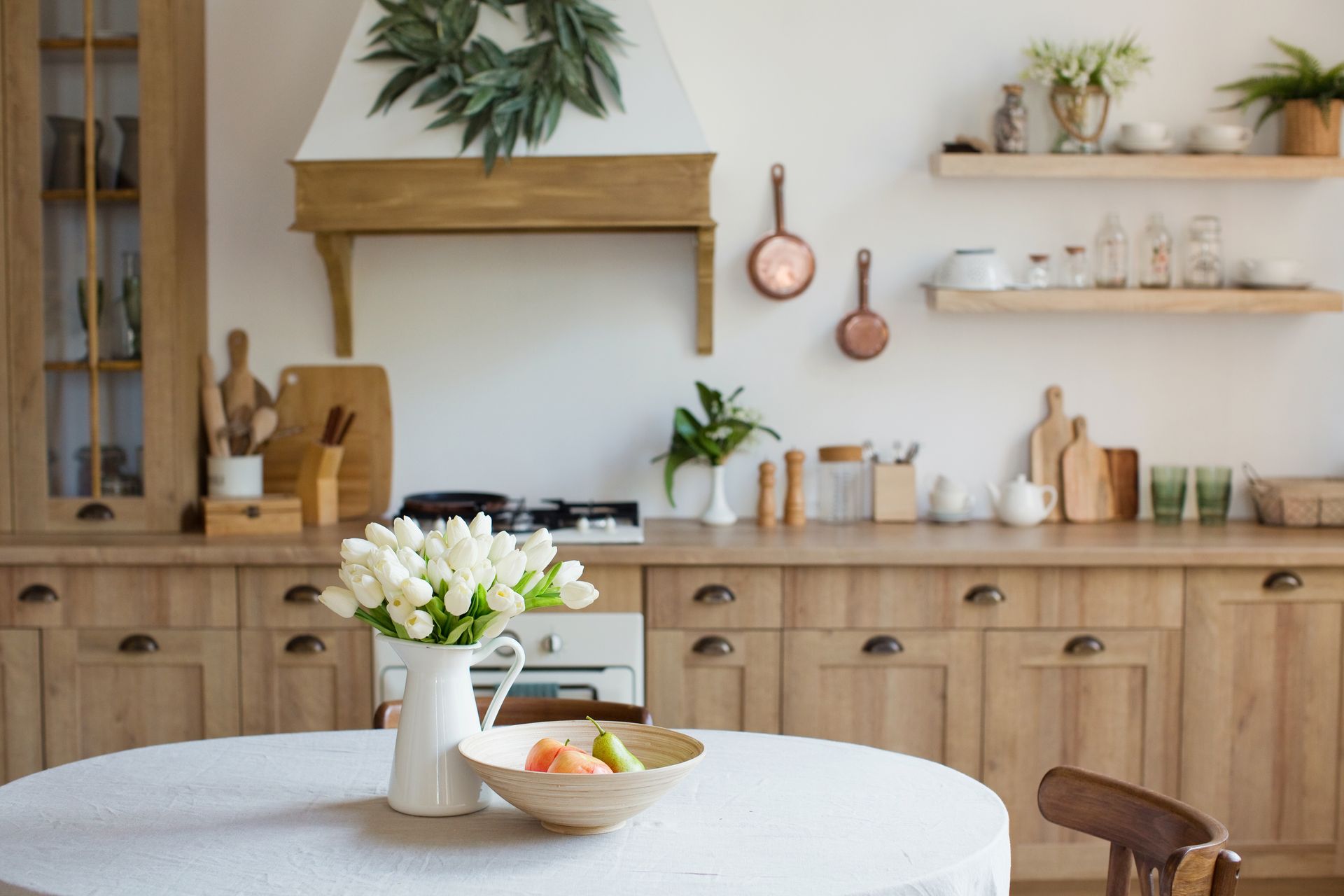 A kitchen with wooden cabinets and a table with a bowl of fruit on it.