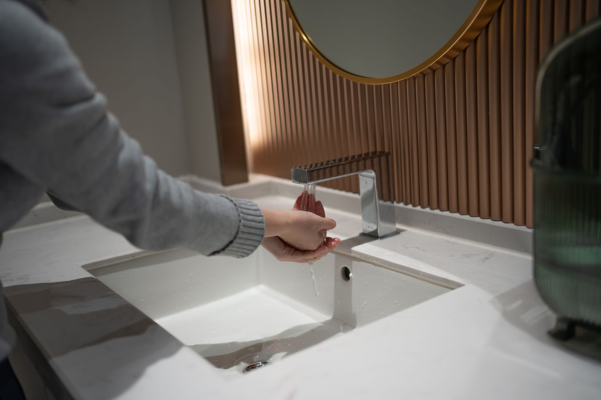 A person is washing their hands in a bathroom sink.