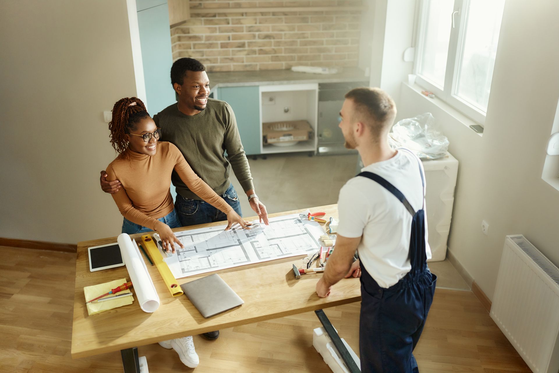 A man and a woman are standing at a table looking at a blueprint.