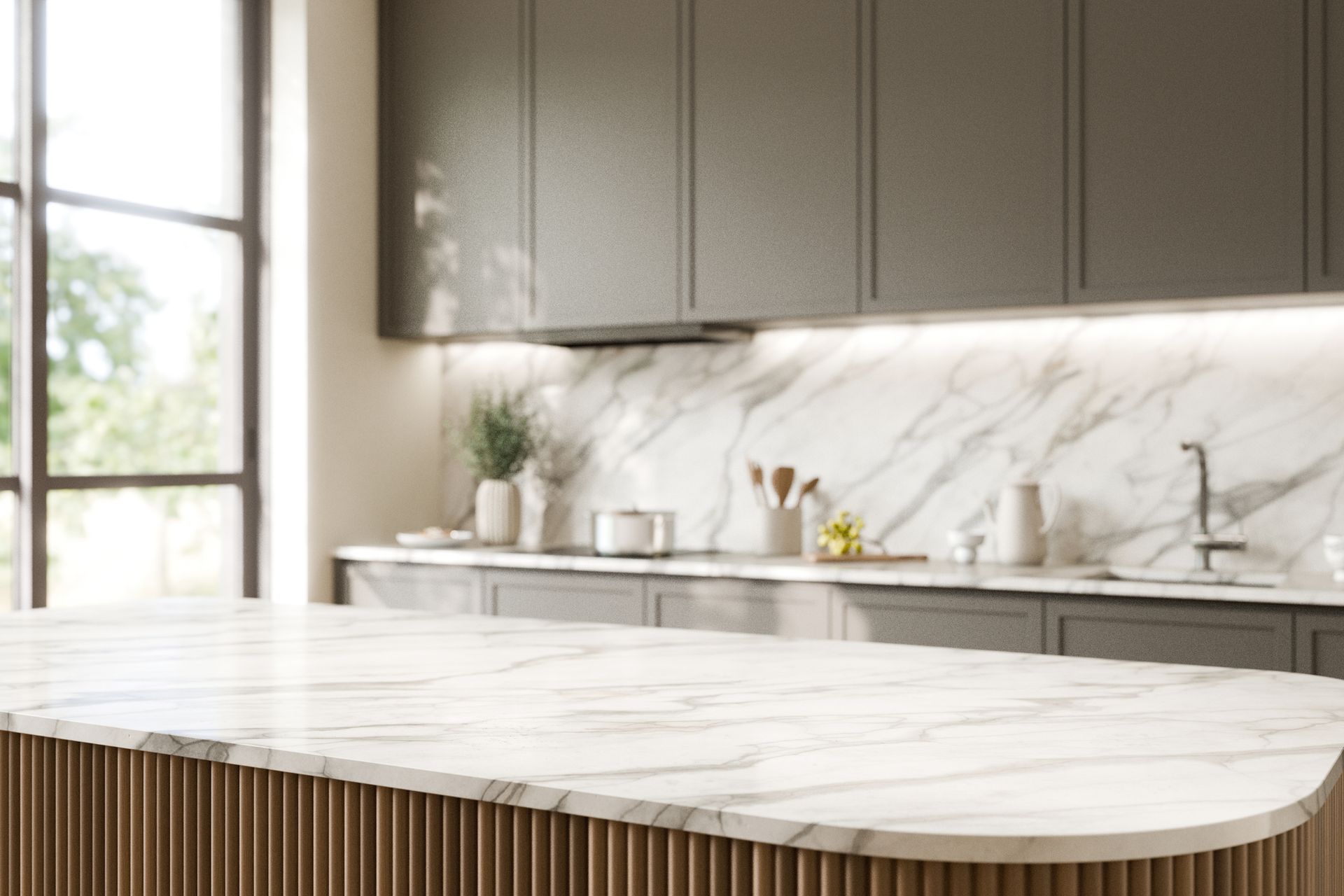 A kitchen with a marble counter top , gray cabinets , and a large window.