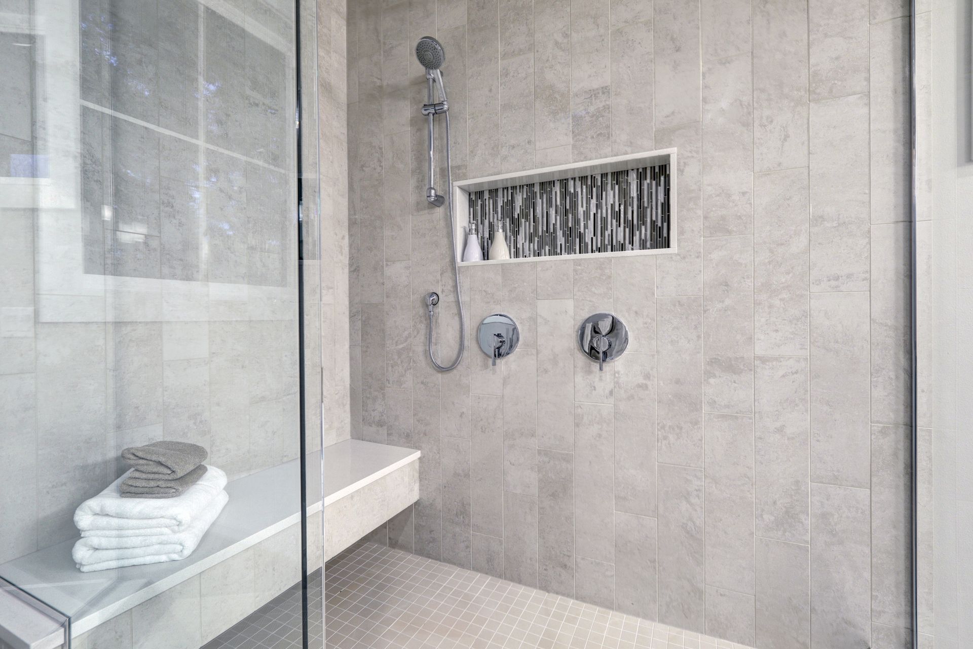 A bathroom with a walk in shower and a bench.