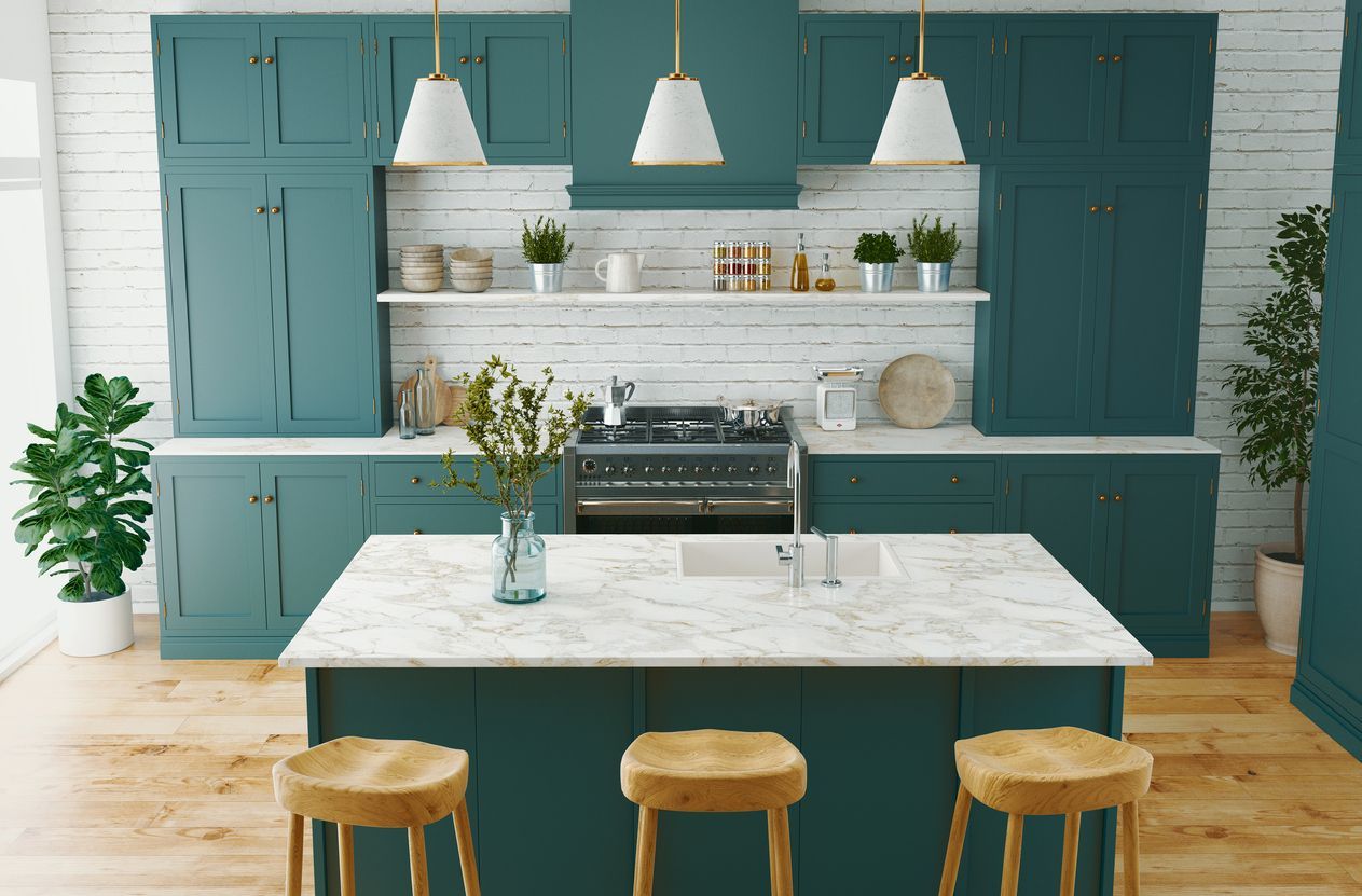 Teal kitchen with white marble island, hanging pendant lights, and three wooden stools