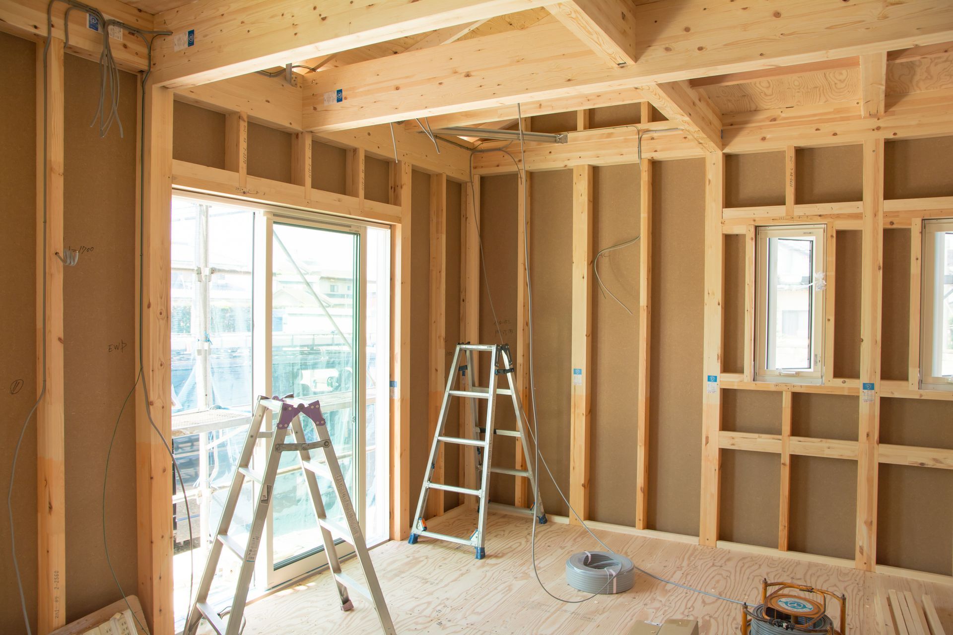 Interior of a building under construction, wooden framing, ladders, and window openings.