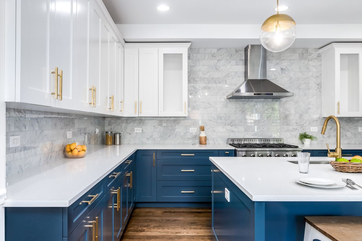 Modern kitchen with white upper cabinets, blue lower cabinets, marble backsplash, and stainless steel appliances