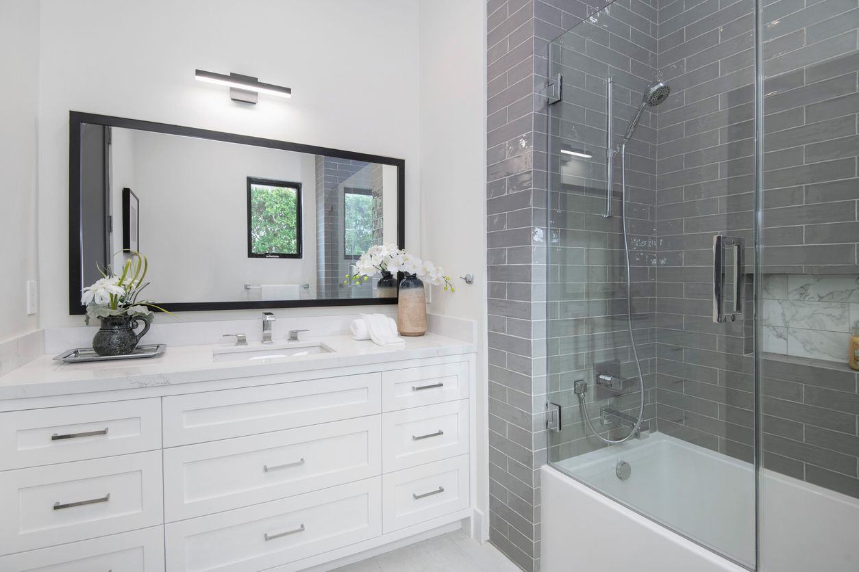 A bathroom with a tub , sink , mirror and shower.