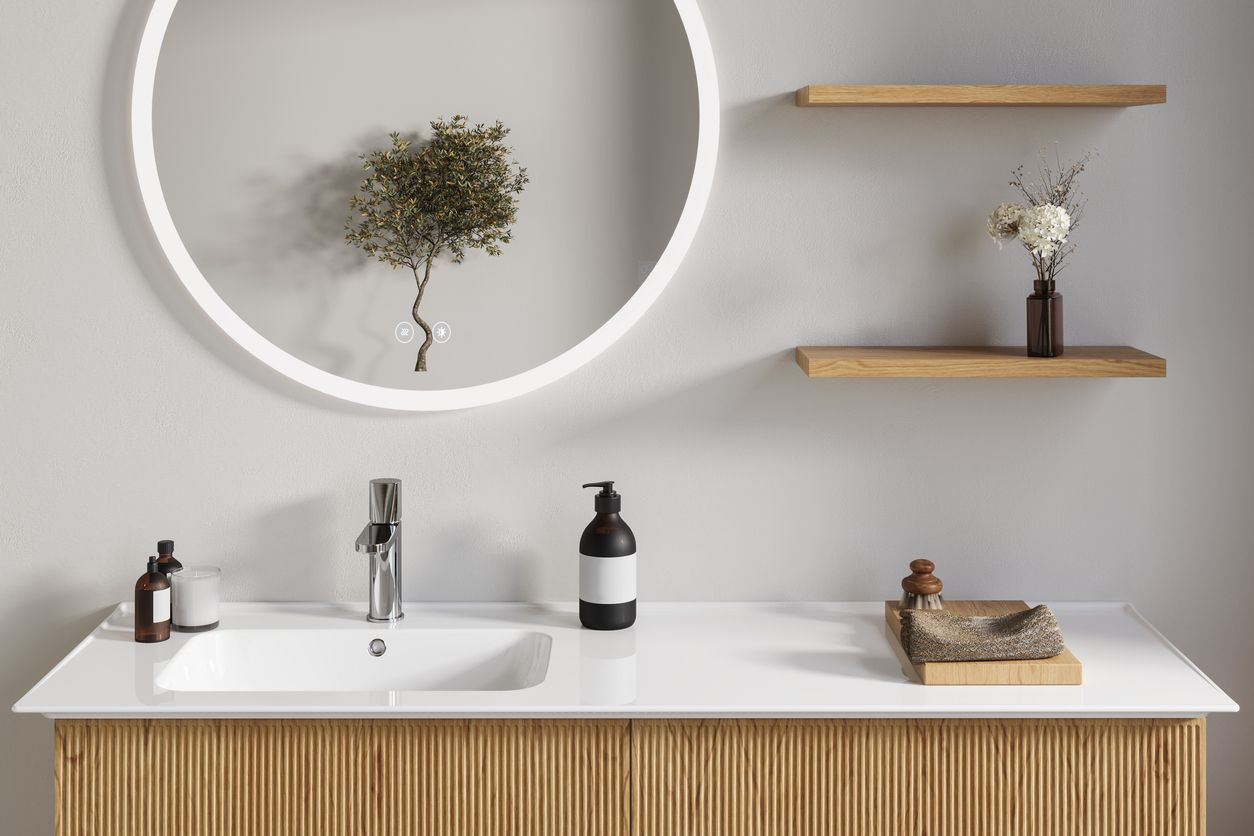 Modern bathroom vanity with round lit mirror, floating shelves, and white sink on wood slat cabinet