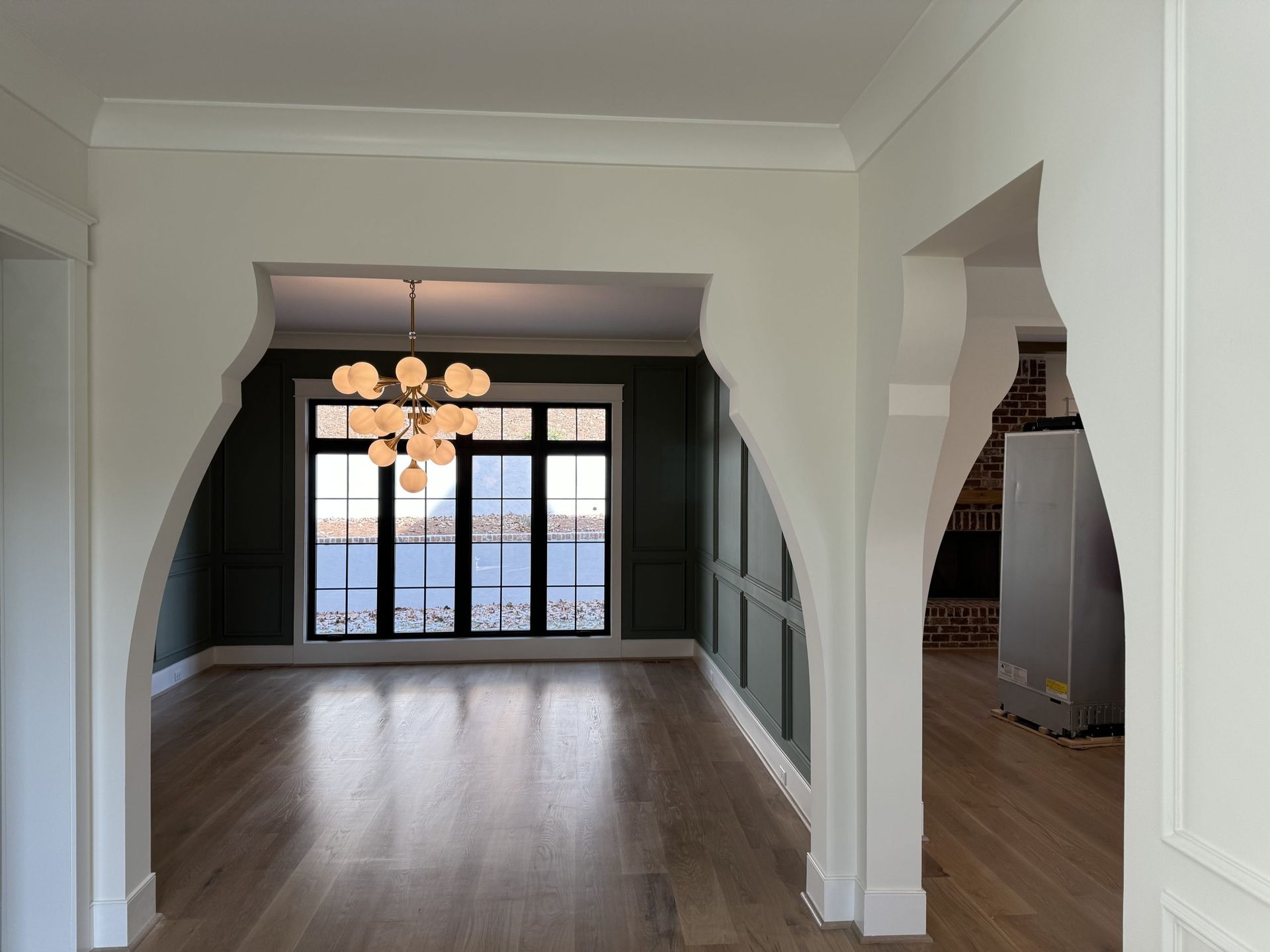 An empty room with a large window and a chandelier