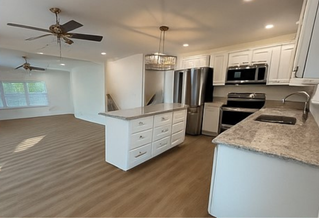 Modern kitchen with white cabinets, stainless steel appliances, and a central island.