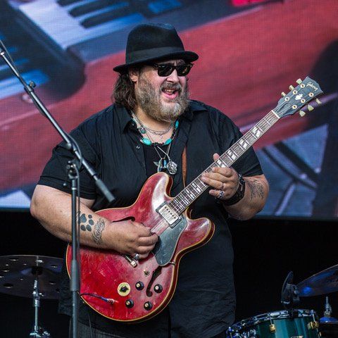 Nick Moss playing a red guitar on stage