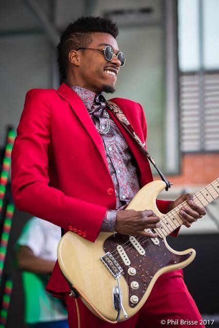 Jamiah Rogers playing the electric guitar and looking dapper in a red suit