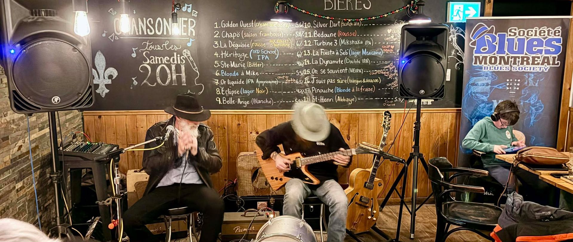 Deux musiciens assis un jouant l'harmonica et l'autre une guitare