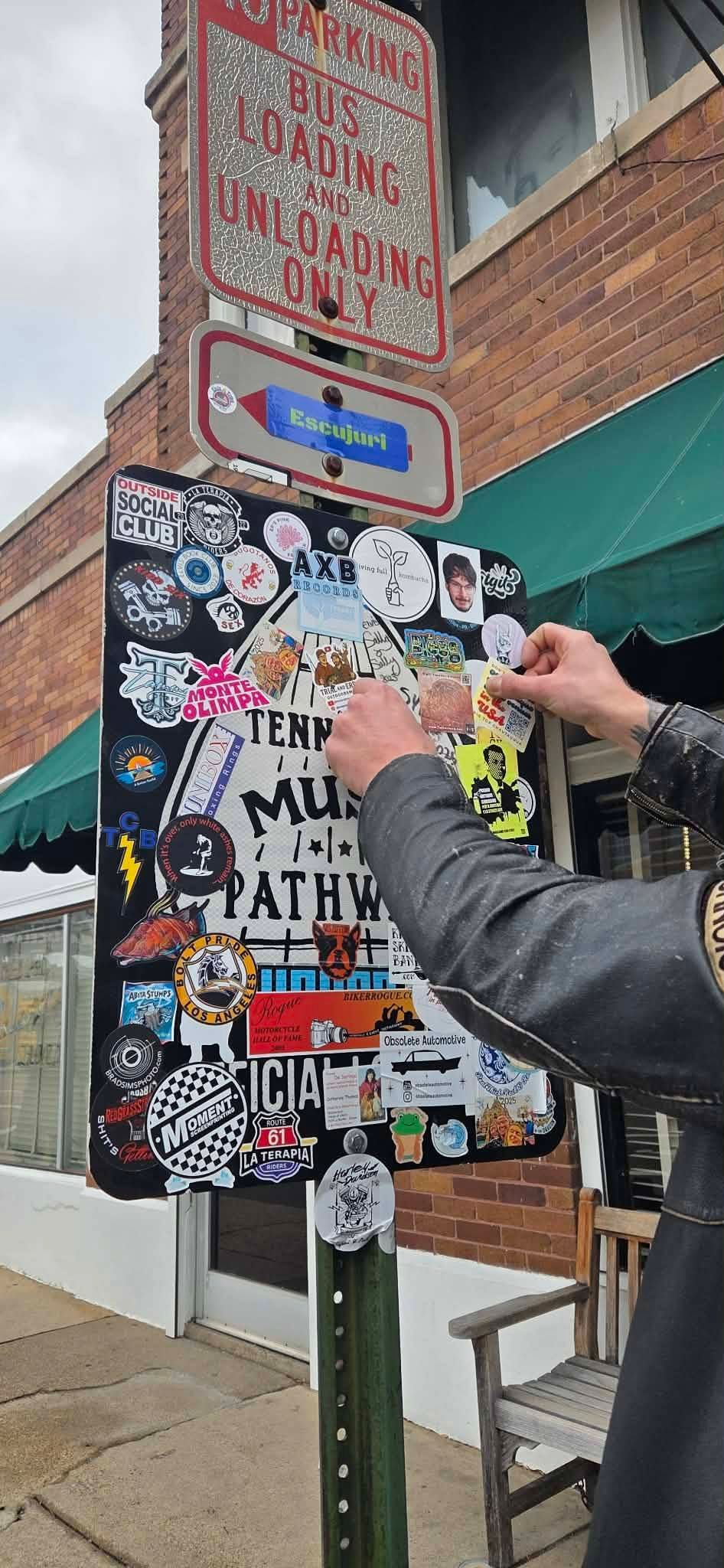 Someone sticking a Father'n'Son sticker on an outdoor sign