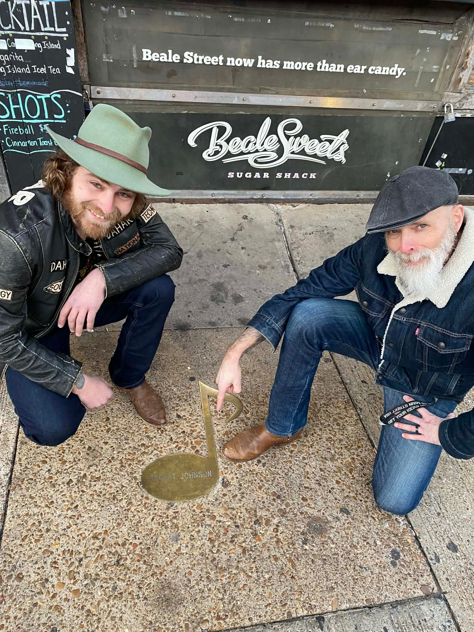 Father'n'Son posing and pointing to a brass musical note embedded in the sidewalk with Robert Johnson's name
