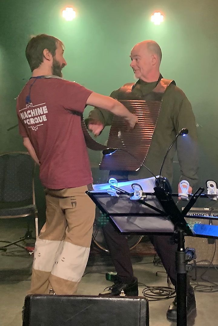 Two men wearing washboards facing each other and playing the other's board