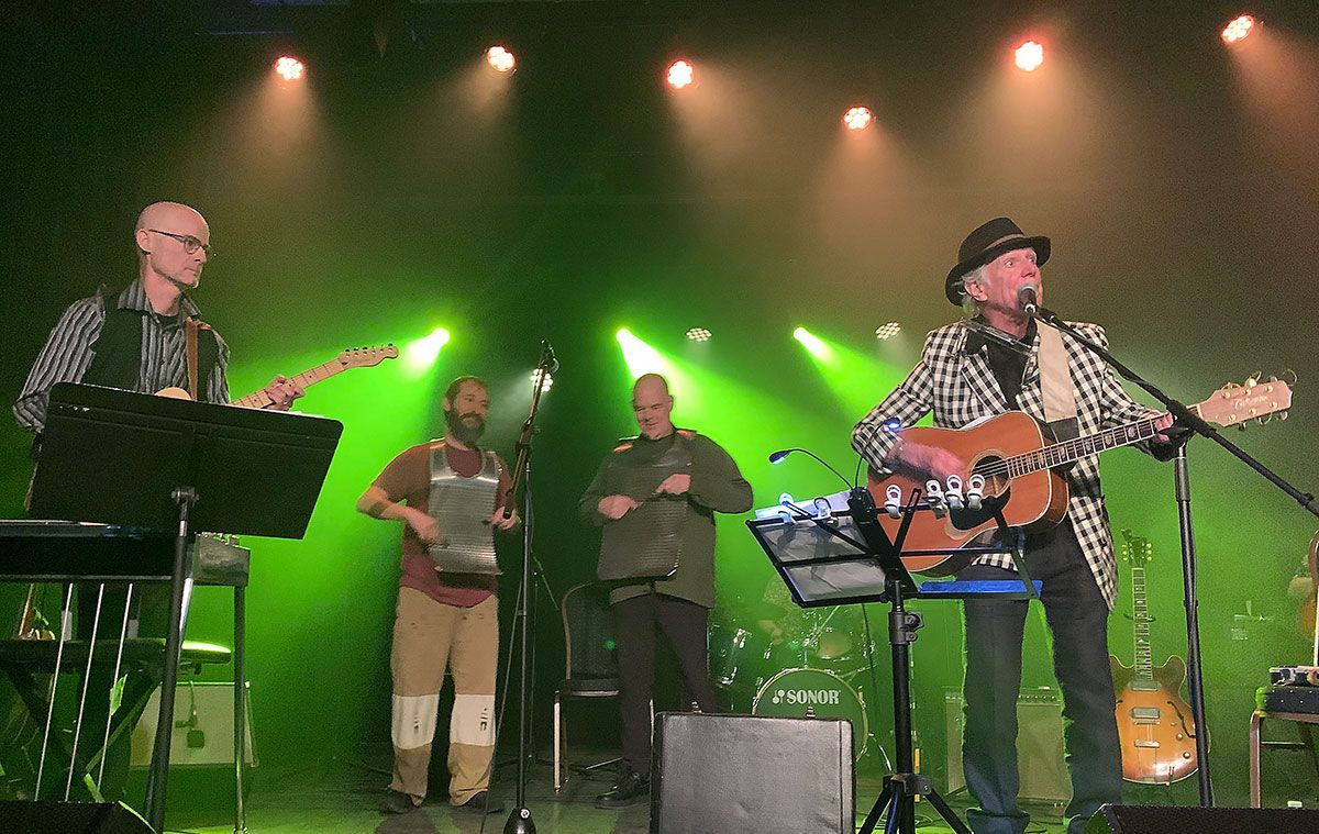 Jay Sewall with 3 other musicians on stage with green back lights