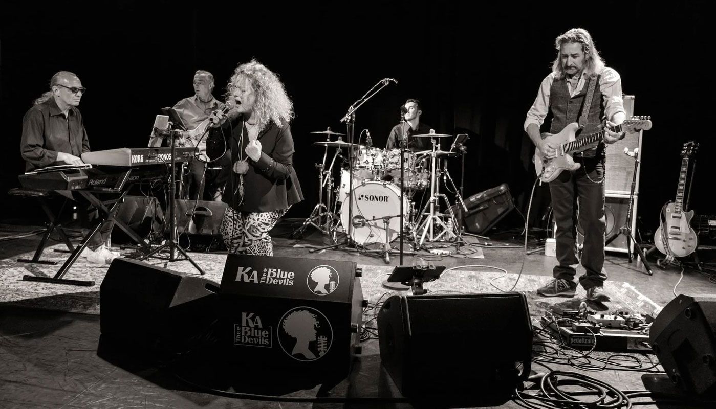 Black and white photo of a band on a stage with a woman singing