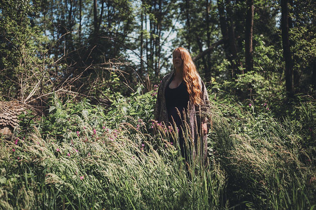 Layla Zoe avec ses longs cheveux roux debout dans une clairière de forêt