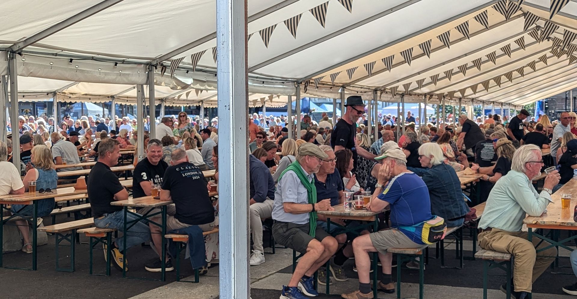 Tent with many people sitting at tables enjoying a drink