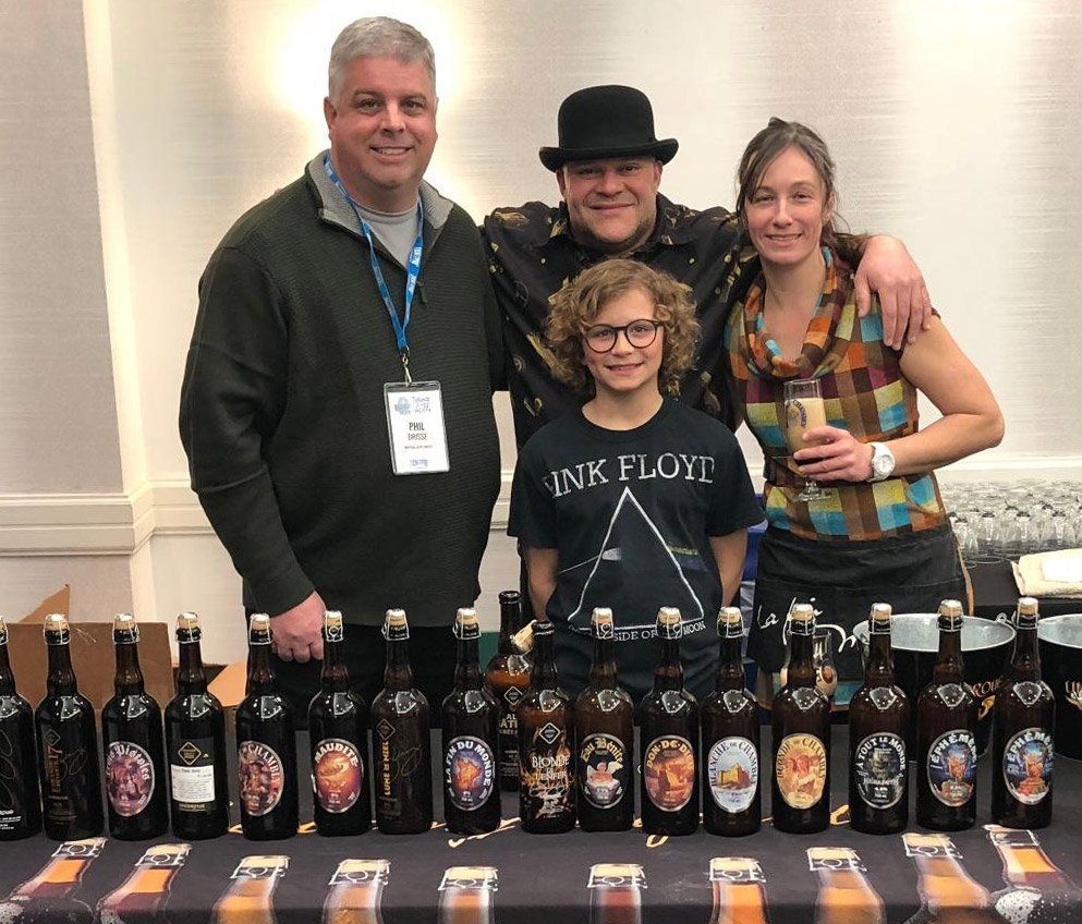 Phil Brisse - the president of the Montreal Blues Society, Jerry Vietz - Brewmaster at Unibrour with his wife and son posing in front of a collection of beer