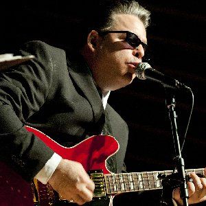 Pat Loiselle on stage playing a red guitar