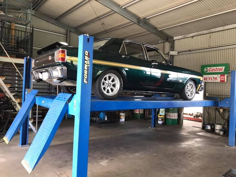 A Classic Green Car is on a Blue Car Lift — Atherton Mechanical Services in Atherton, QLD