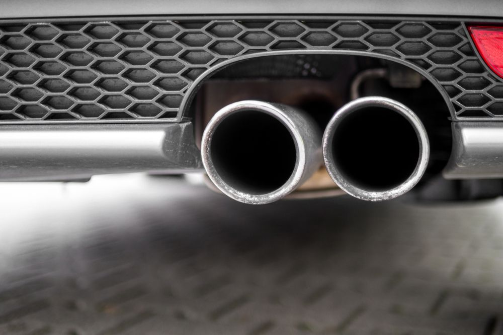 Dual Exhaust Pipes On A Car, Close-up With Black Honeycomb Detail And A Red Taillight Partially Visible — Atherton Mechanical Services in Atherton, QLD