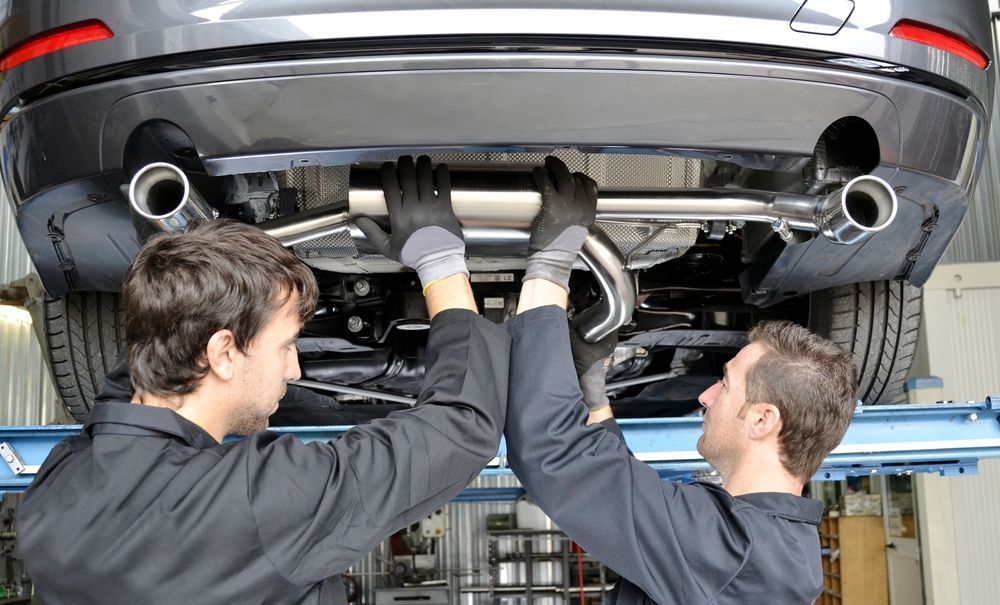 Mechanics Installing a Car Exhaust System While the Vehicle is on a Lift — Atherton Mechanical Services in Port Douglas, QLD