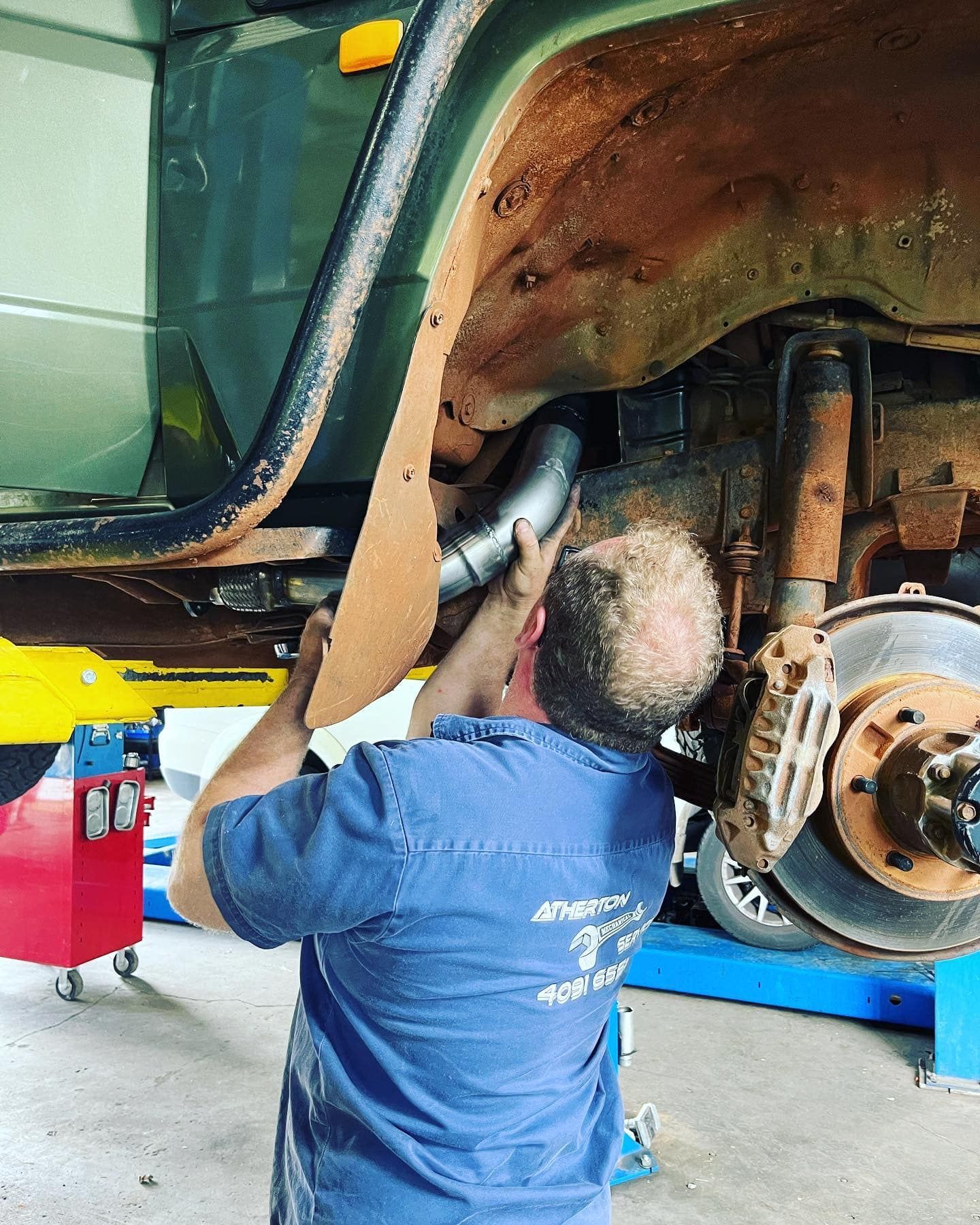 Red And Black Toy Atv On A Car Lift In A Repair Shop — Atherton Mechanical Services in Atherton, QLD