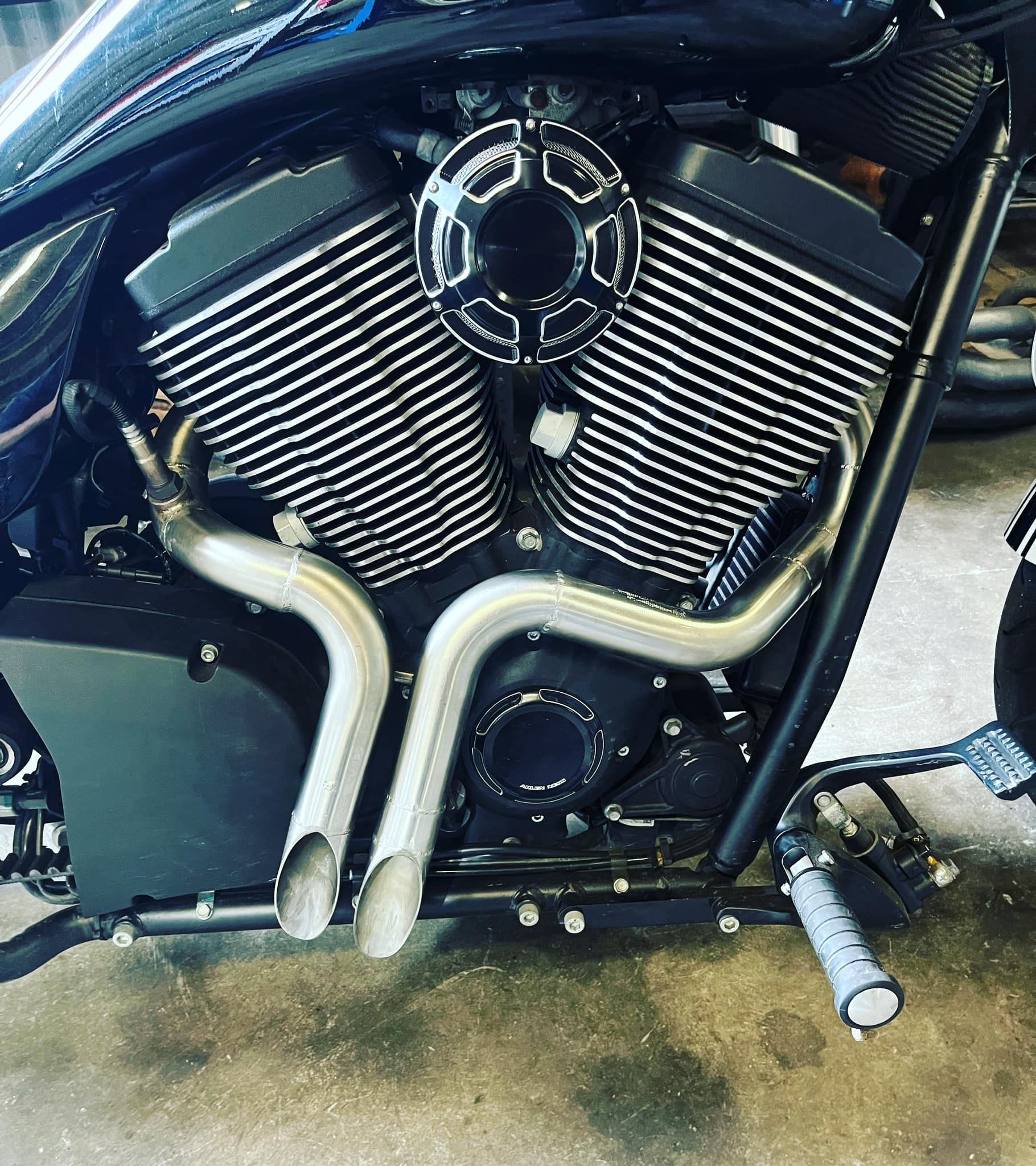 Black Motorcycle Engine With Silver Exhaust Pipes — Atherton Mechanical Services in Cairns, QLD