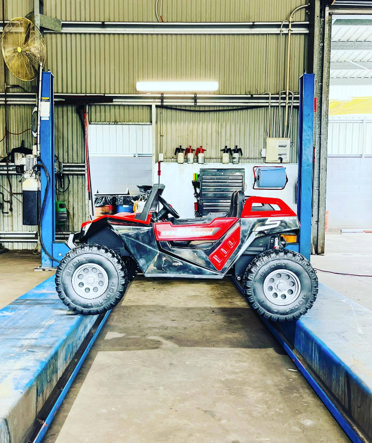 Red And Black Toy Atv On A Car Lift In A Repair Shop — Atherton Mechanical Services in Atherton, QLD