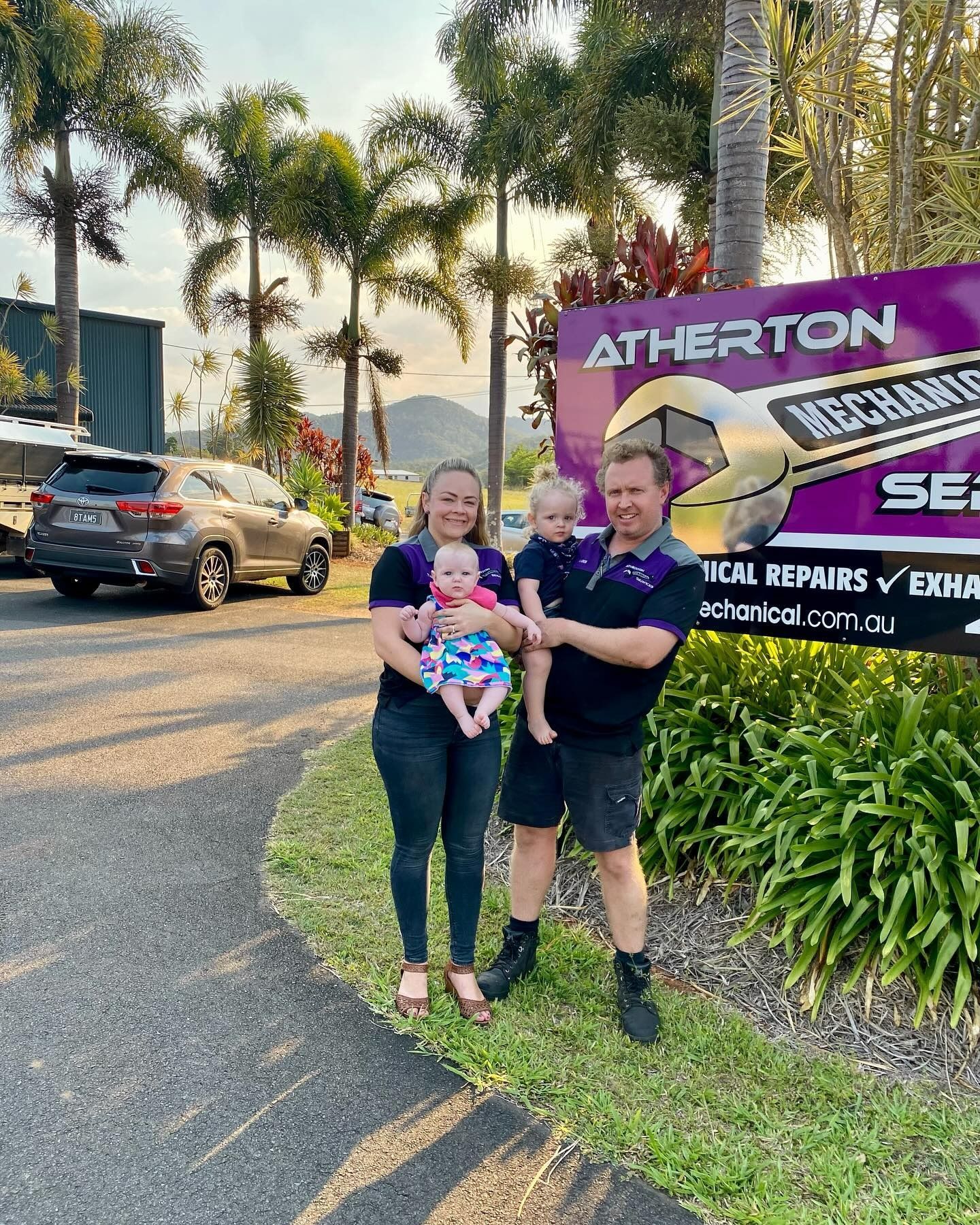 Family Stands In Front Of A Mechanic Shop Sign. Mother Holding Baby, Father Holding Toddler — Atherton Mechanical Services in Atherton, QLD