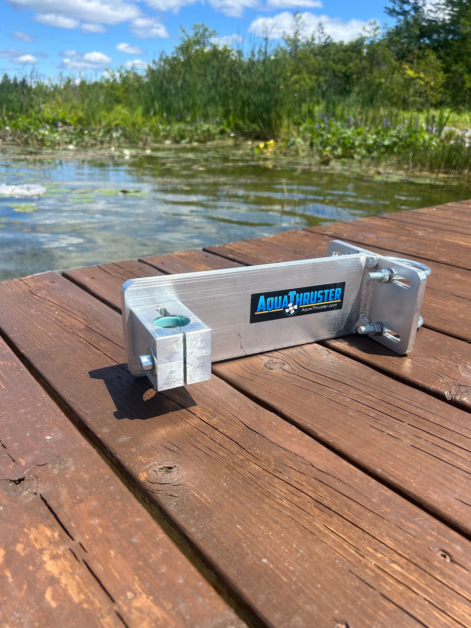 Aluminum dock bumper with blue logo, on wooden dock near water.