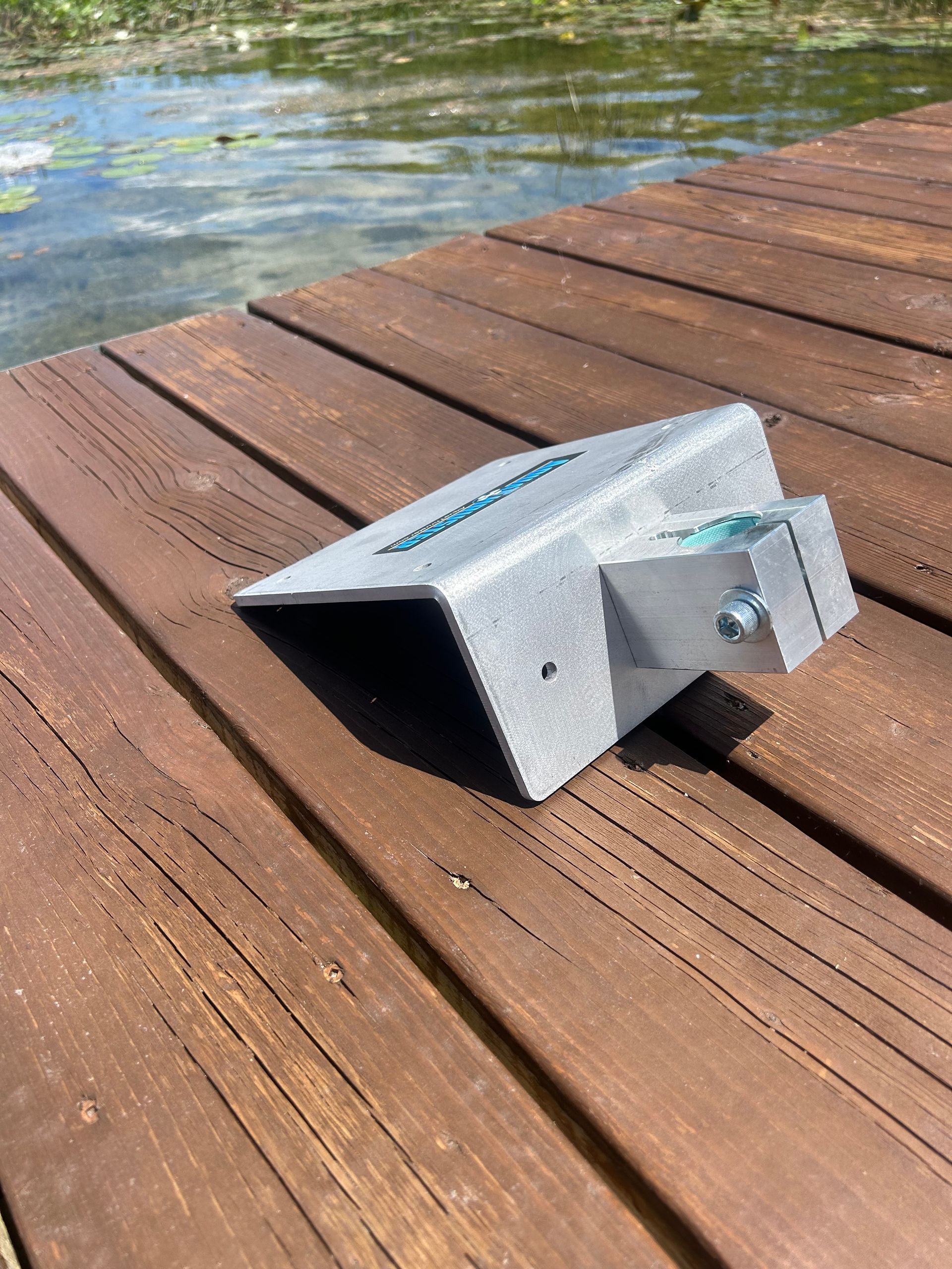 Silver AquaThruster device on a wooden dock by a lake.
