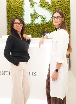 Due donne sono in piedi una accanto all'altra davanti a un muro verde.