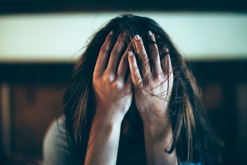 Una donna si copre il viso con le mani.