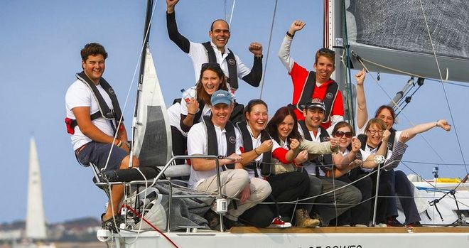 Un gruppo di persone posa per una foto su una barca a vela.
