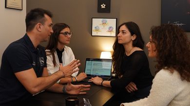 Un gruppo di persone è seduto attorno a un tavolo e parla tra di loro.
