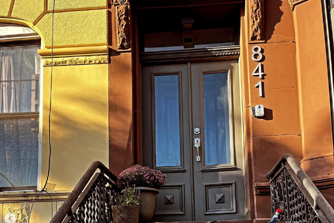 The entrance to an old brownstone building with steps and a dark-colored double door marked with the number 841.