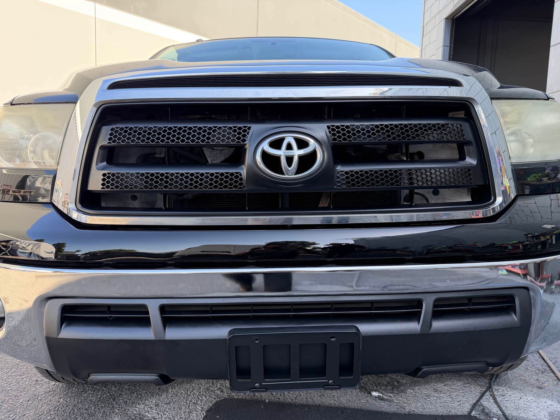 Black Toyota Tundra truck front view, showing grille with Toyota logo and license plate holder.