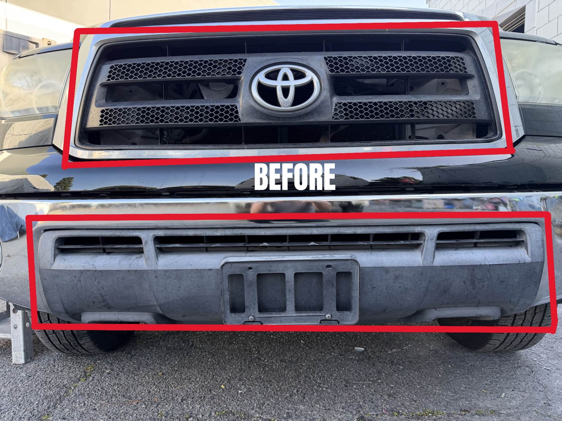 Black Toyota truck front with grill, emblem, and bumper, parked on pavement.
