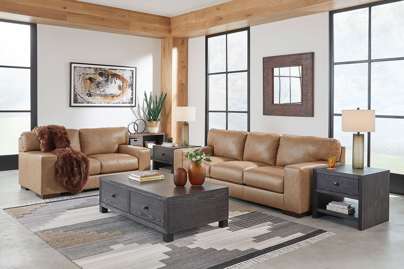 Living room with tan leather sofas, dark wood coffee table, and large windows.