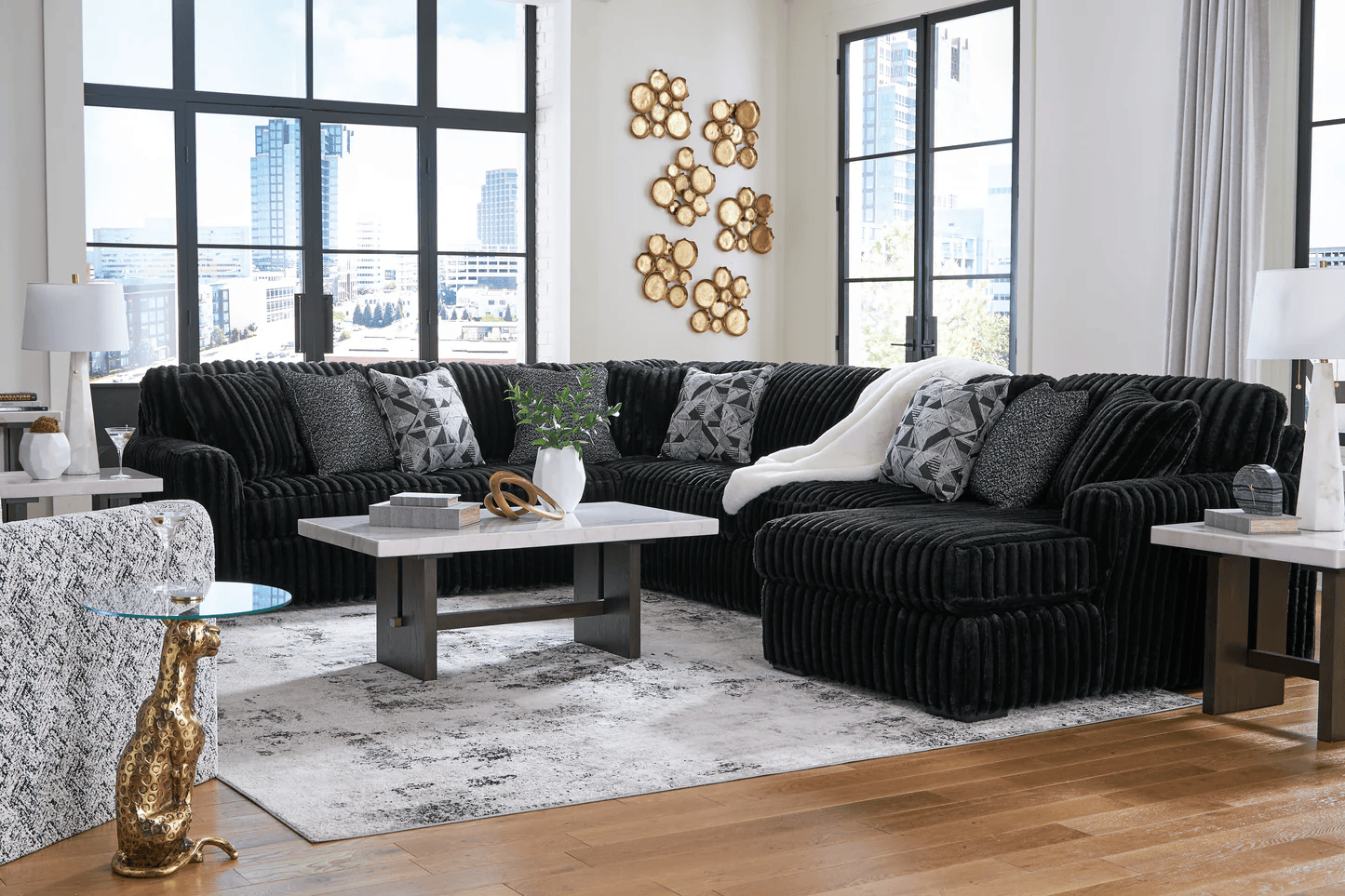 Living room with black sectional sofa, marble coffee table, and cityscape view.