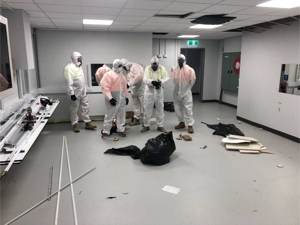 A Group of People in Protective Suits Are Standing in a Room — Shedquarters In Kirwan, QLD
